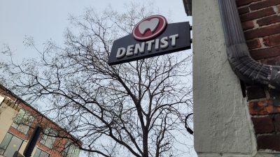 a dentist sign hanging off the side of a building