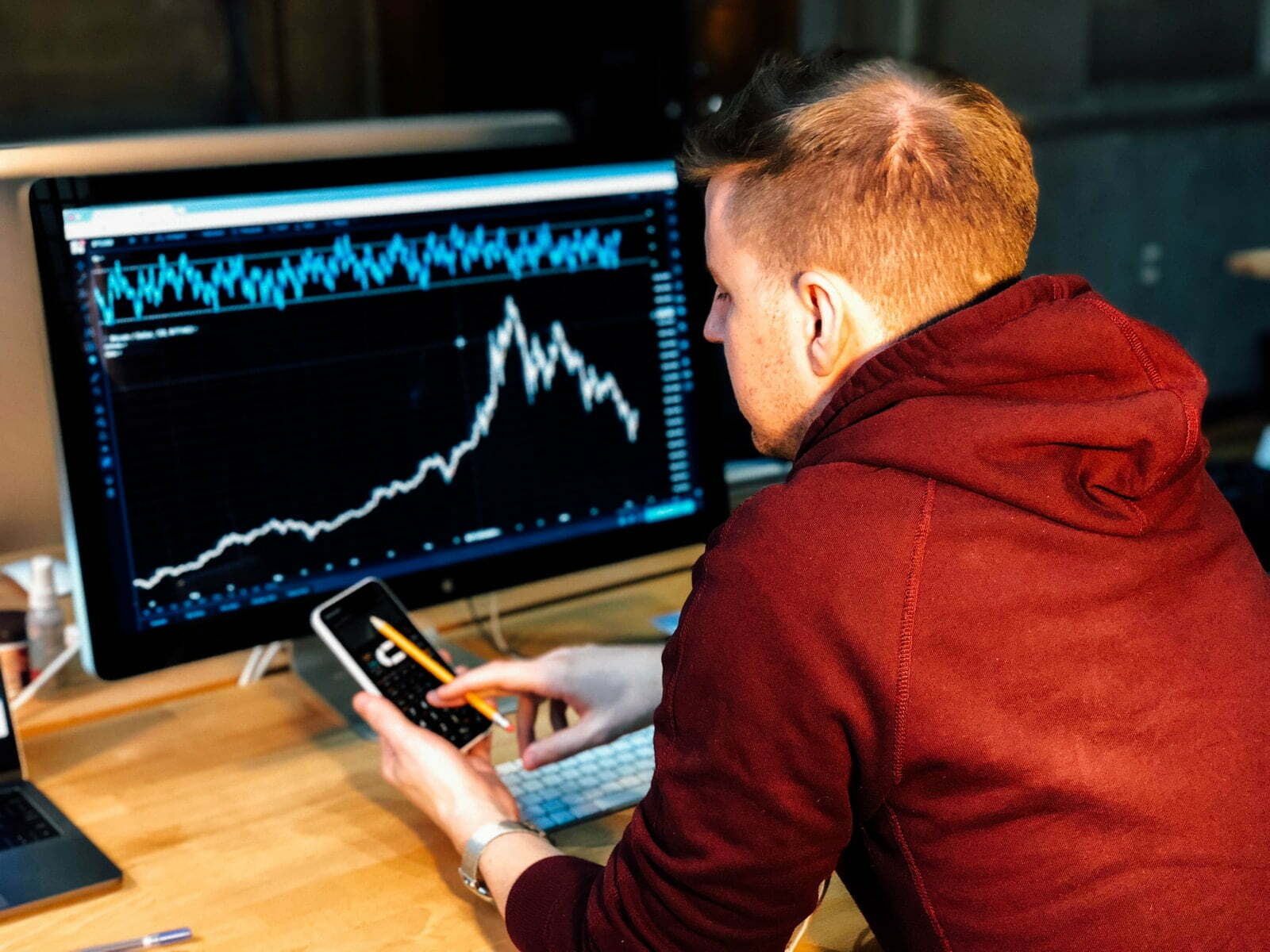 Make more money with these 5 tech side hustles man holding black smartphone with flat screen monitor in front