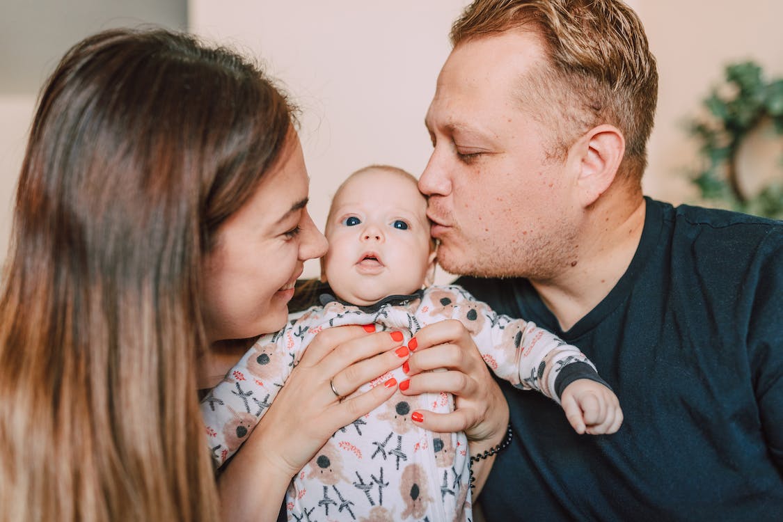 7 Things You Can Do for Your Newborn’s Good Health Free A Mother Carrying Her Baby while a Man Kissing the Baby Stock Photo