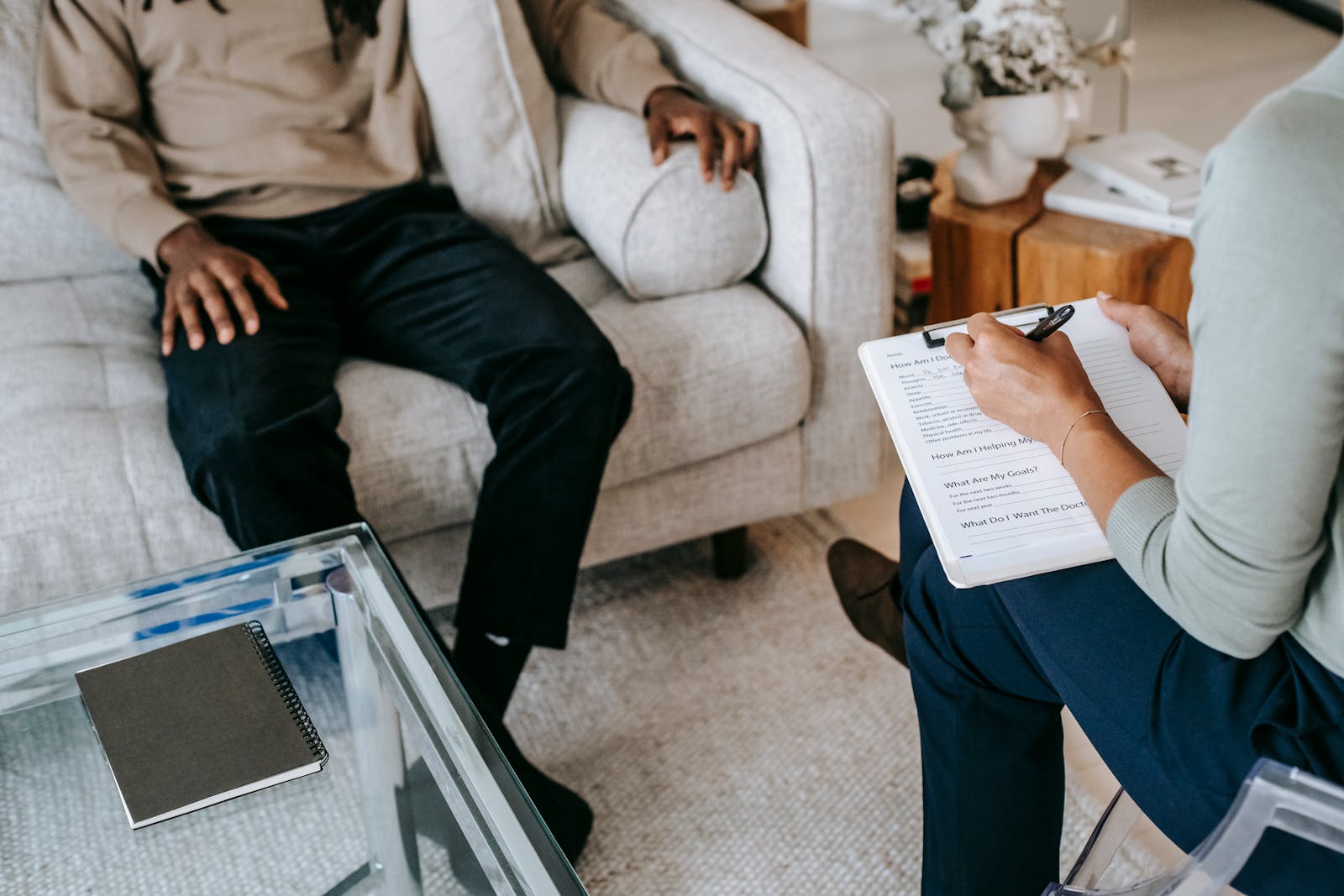 The Role of Mental Health Therapists in Overcoming Life's Challenges From above crop African American male in casual clothes sitting on comfy couch and answering professional female consultant questions in modern psychotherapy office