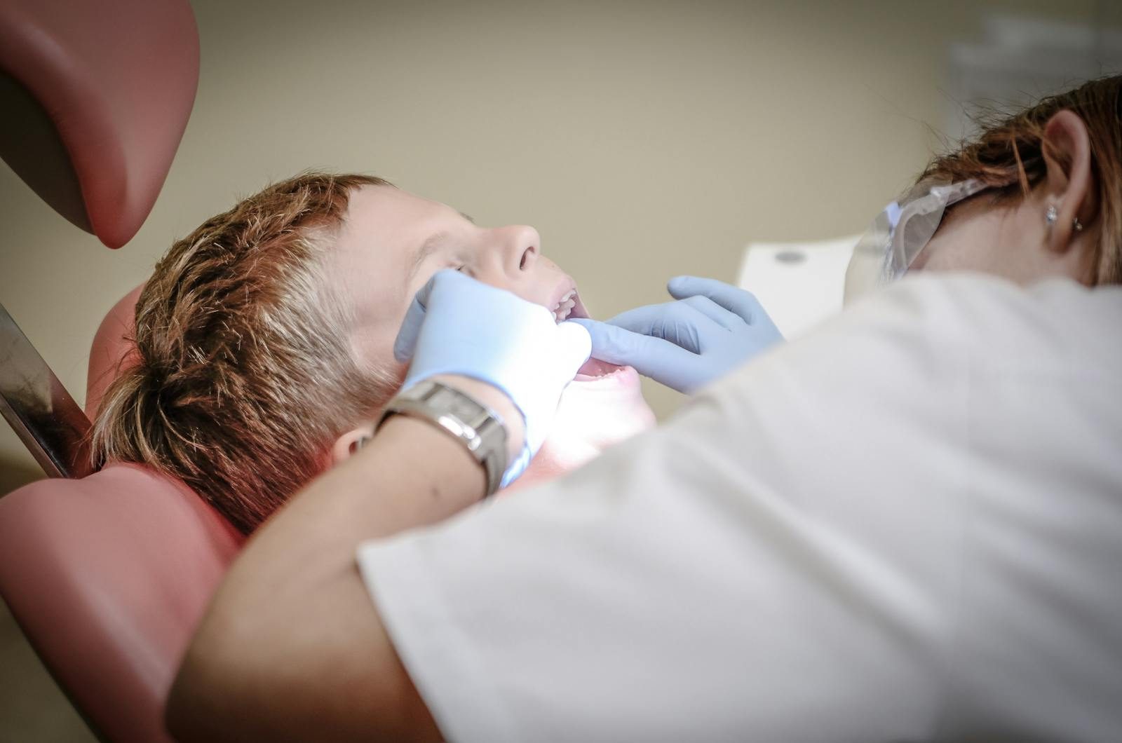 3 Ways Family Dentists Encourage Kids To Take Responsibility For Oral Hygiene A young boy receiving a dental examination by a professional dentist in a clinic setting.