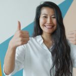I thought life sucks, so I studied positive thinking. Now I’m positive. Woman giving two thumbs up with a smile